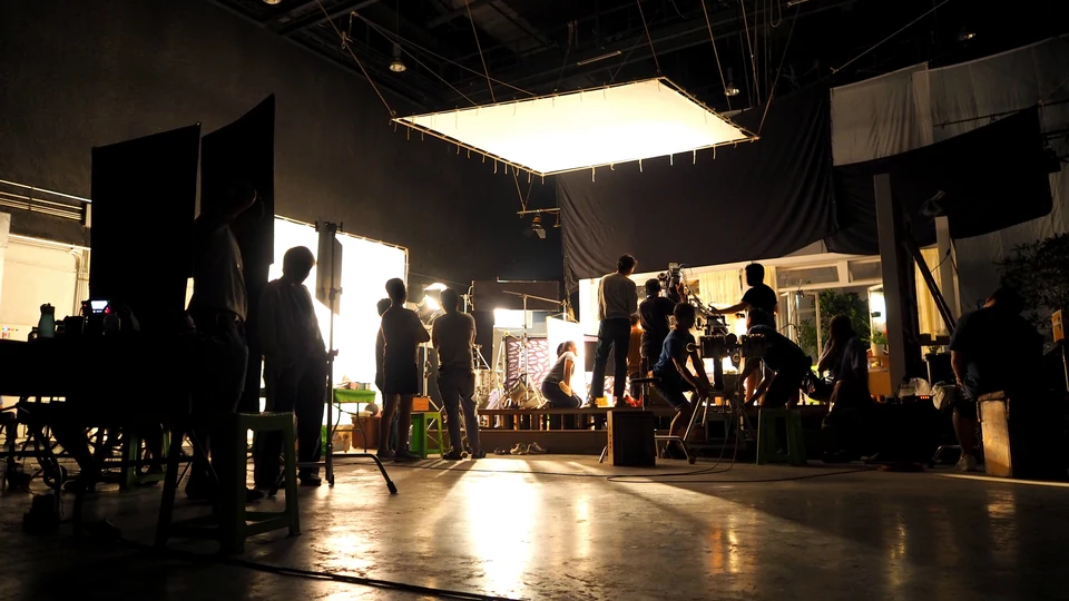 A film crew working on a large, dramatically lit studio set.