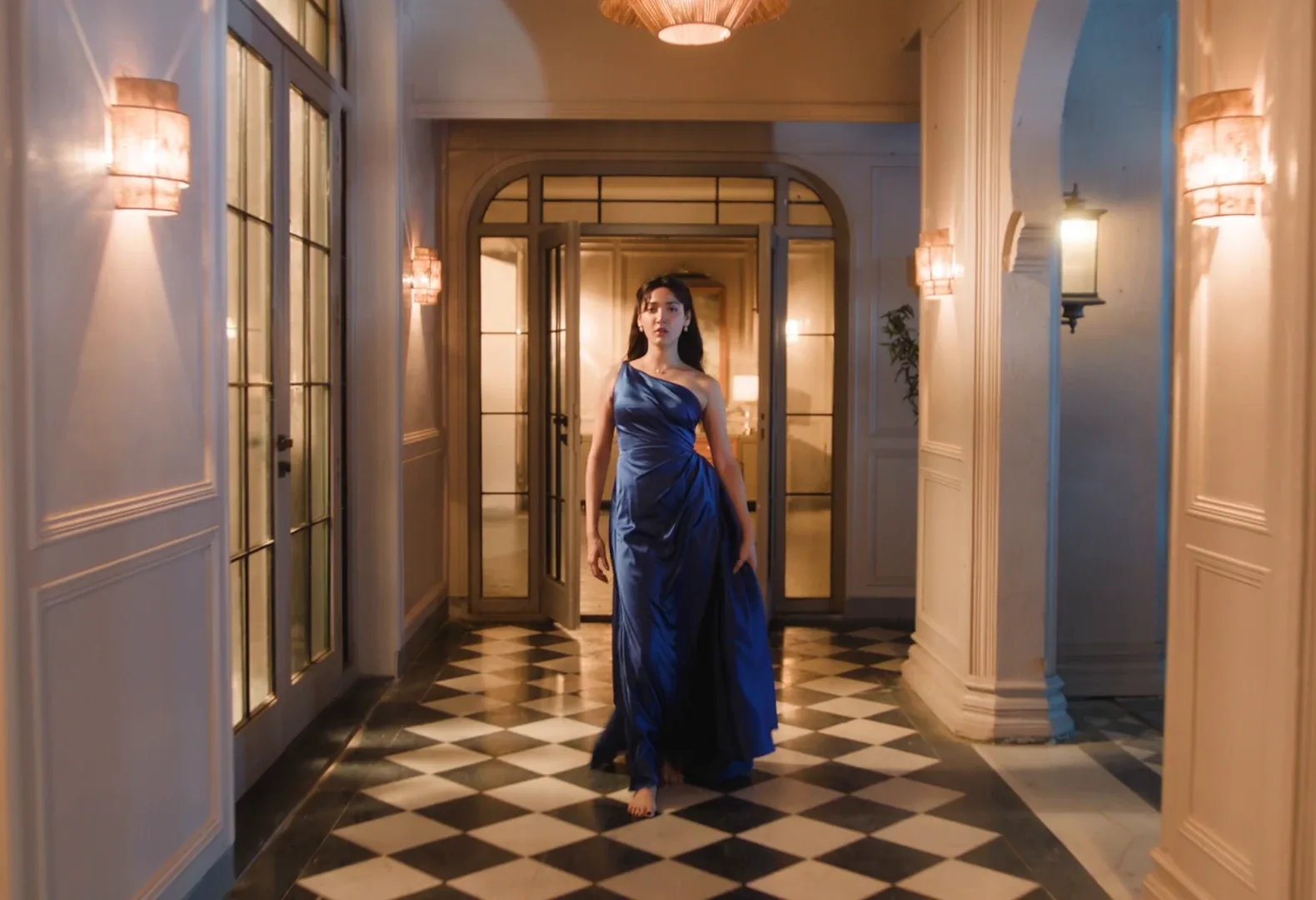 A woman in a blue gown framed by a warmly lit doorway in BLUE STONE.